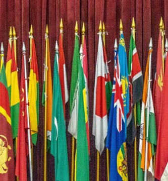 A vibrant collection of diverse national flags arrayed indoors on flagpoles.